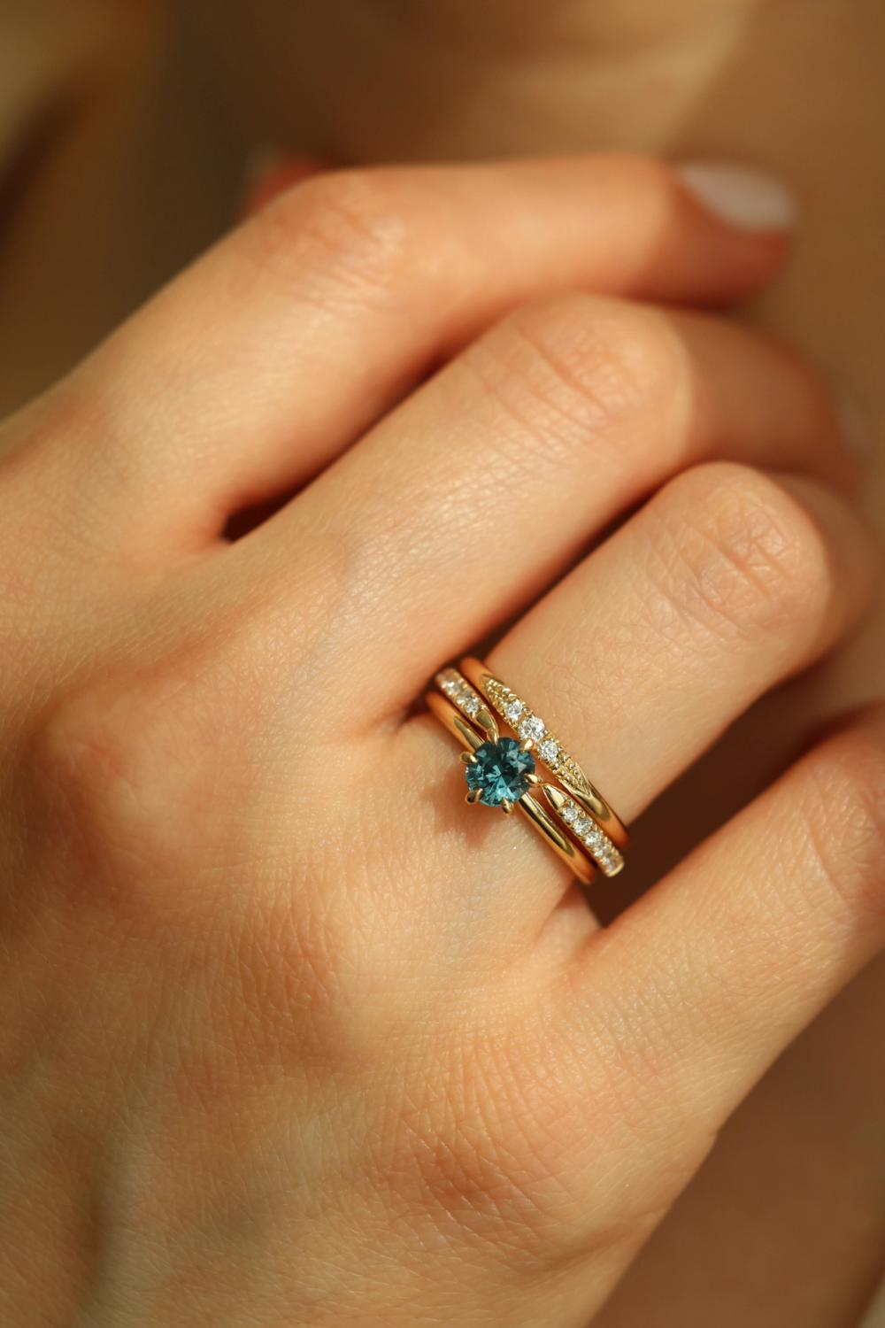 Solitaire ring blue sapphire set in yellow gold stacked with thin gold bands with lab-grown diamonds