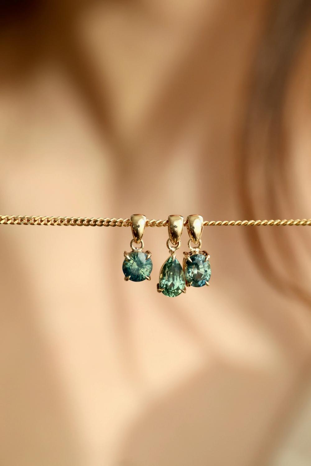 Oval, pear and round green sapphire pendants in yellow gold on a necklace