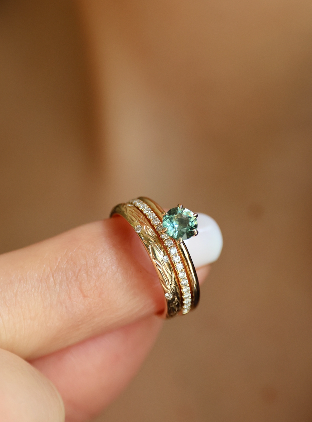 Forlovelsesring med grønn safir i 14 karat gult gull, stablet med diamantringene Swan Band og Sparkling Textured Love Band fra Nangi