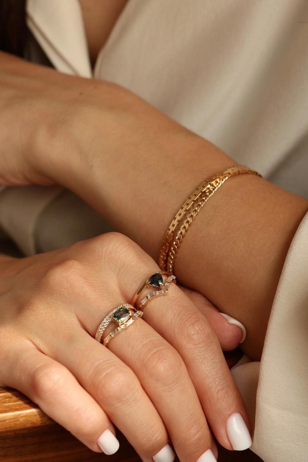 Sapphire rings in solid gold stacked with gold bracelets 