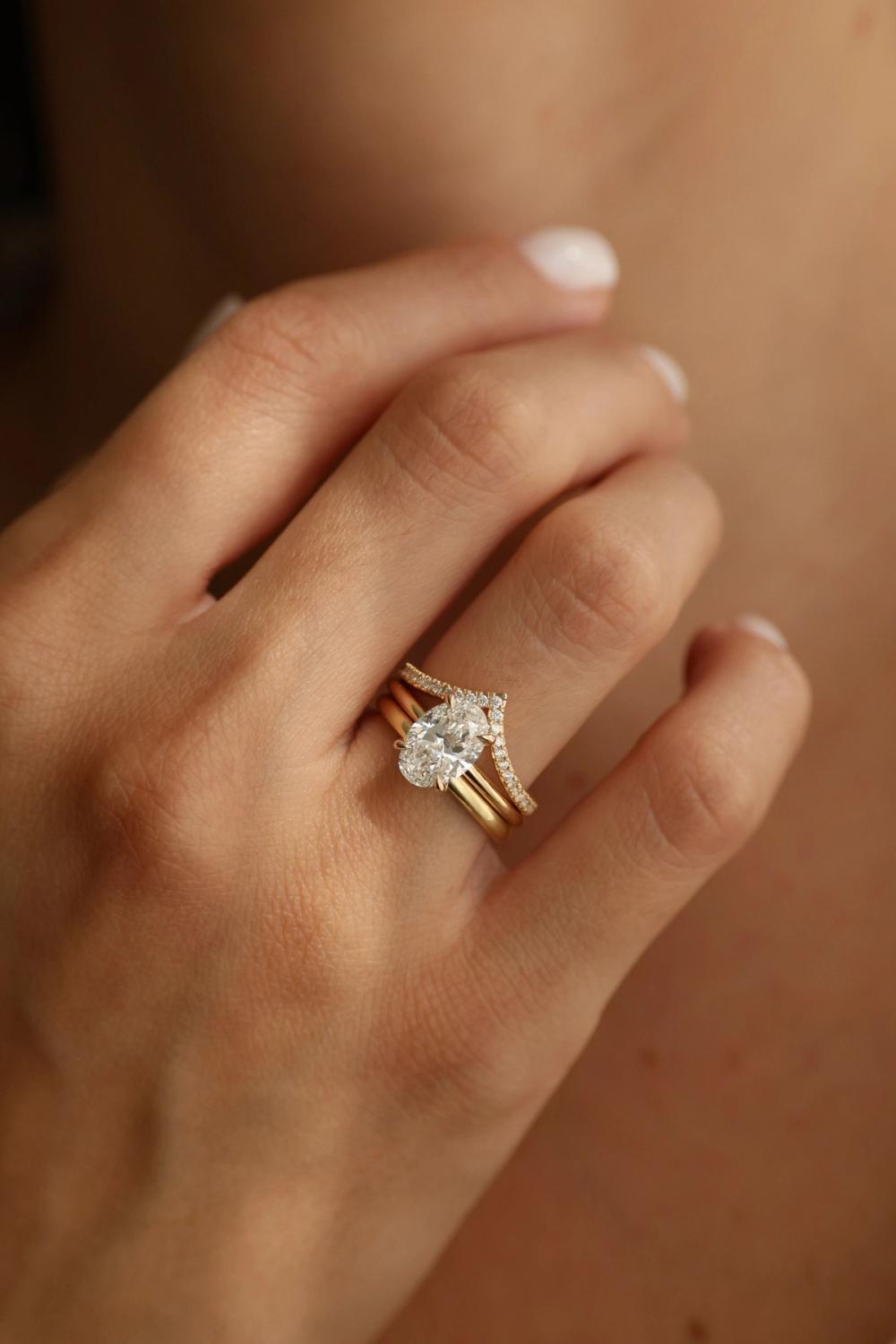 Forlovelsesring med oval labdyrket diamant i gult gull kombinert med en buet giftering med diamanter, fra Nangi.