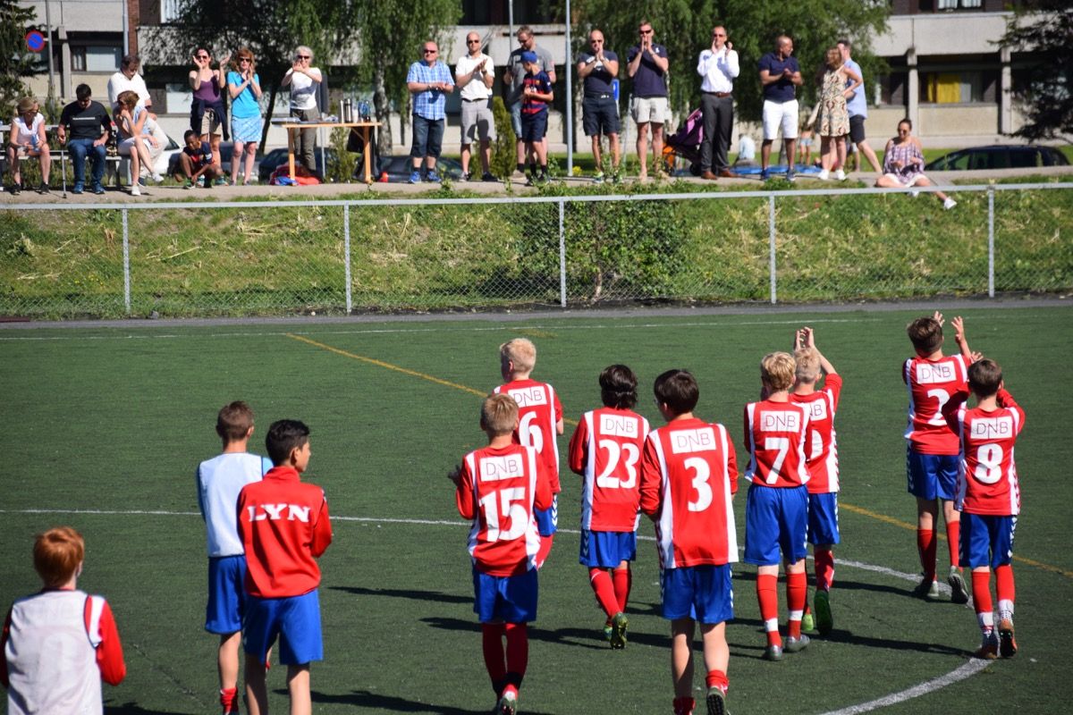 Unge fotballspillere på vei av banen mens foreldrene applauderer fra tribunen