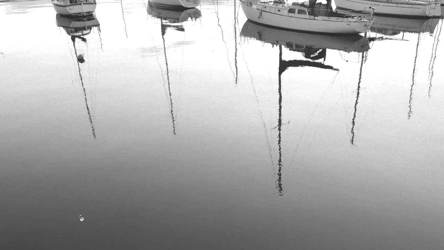 Yachts reflected in still harbour water at dawn