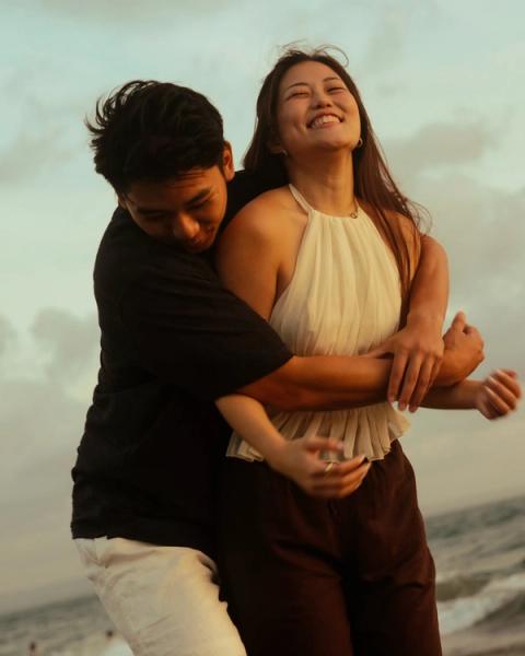 Close embrace on the beach with the woman laughing in warm evening light