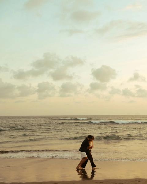 Couple embracing barefoot at the edge of the surf during golden hour in Bali