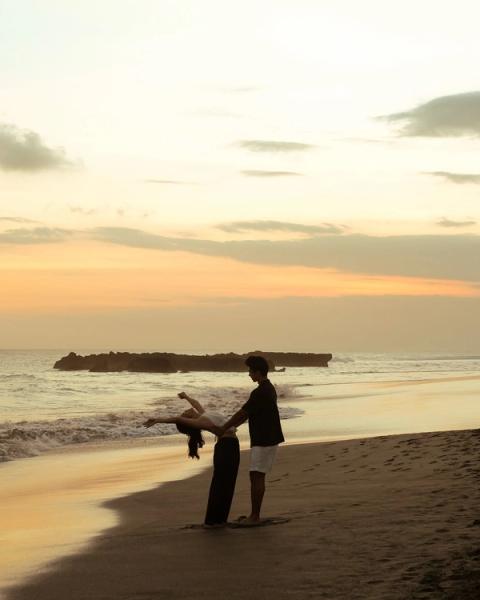 Couple dancing in silhouette on the beach as the sun sets over the ocean