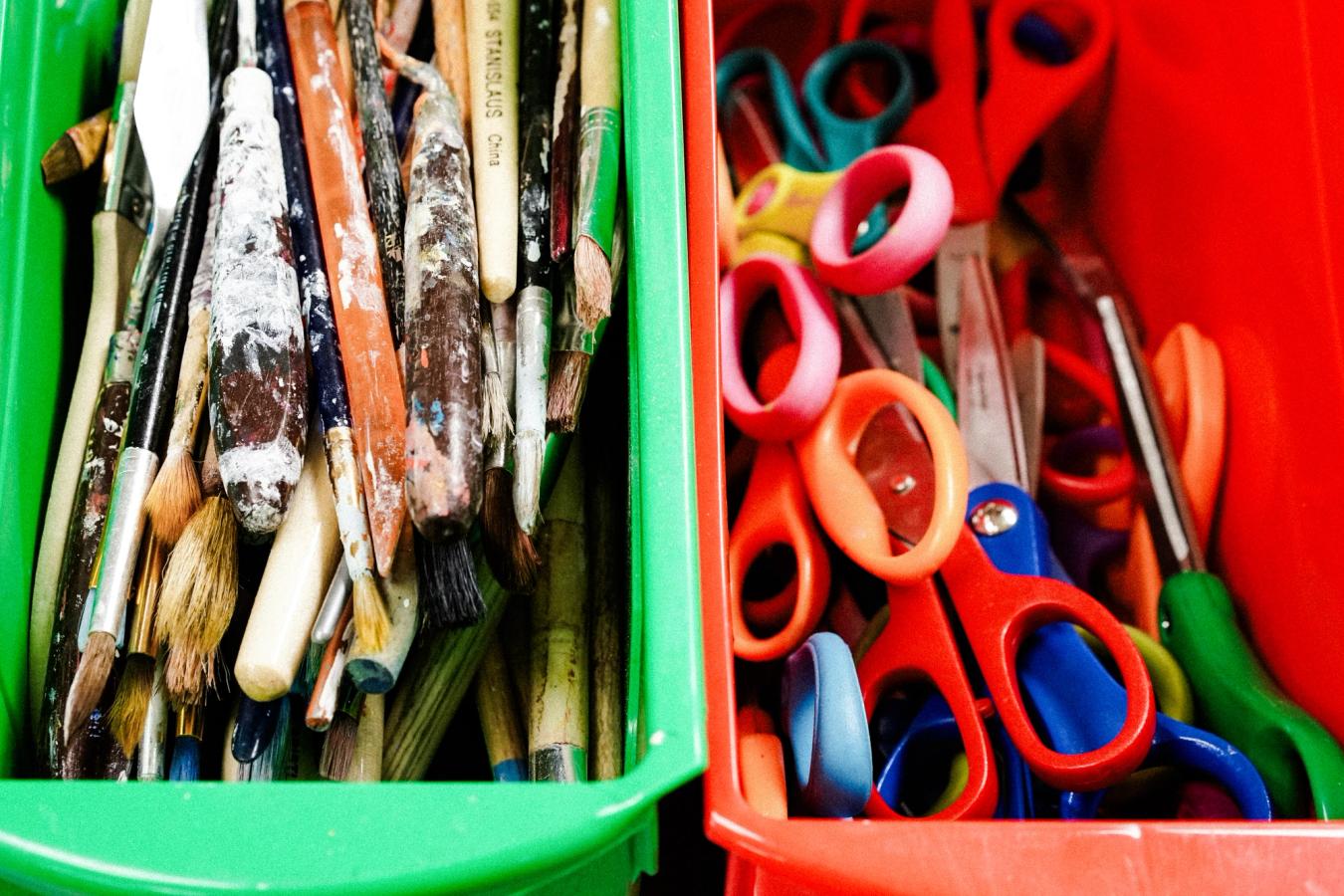 Bilde av malepensler og sakser, trolig i et klasserom