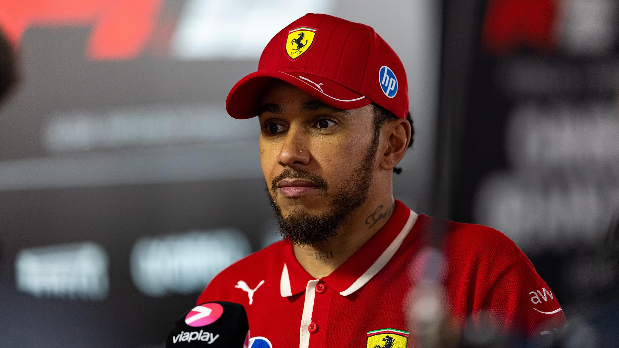 Lewis Hamilton wearing a red Ferrari cap and polo shirt during an interview.