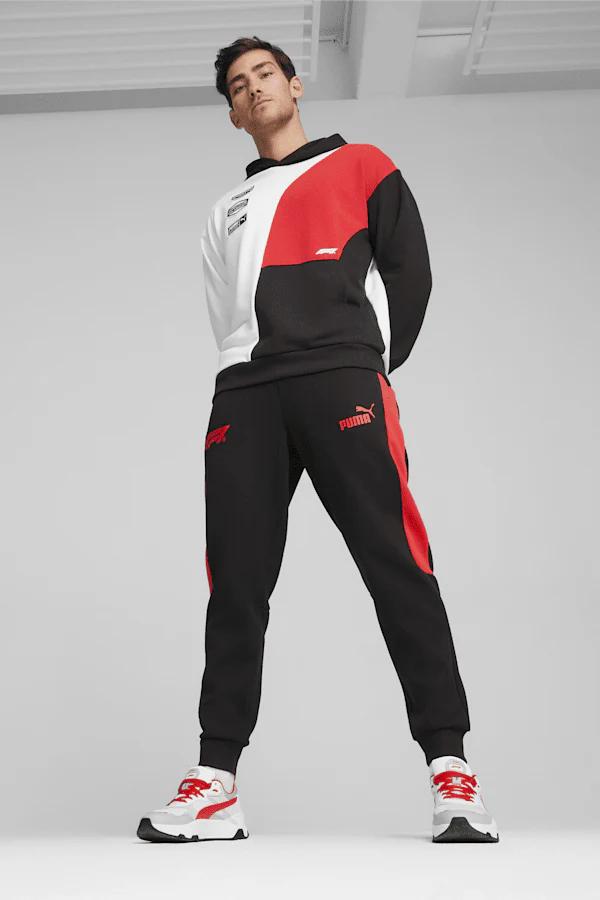 Man wearing a PUMA F1 white, red, and black color-blocked hoodie and black sweatpants with red accents and white sneakers.