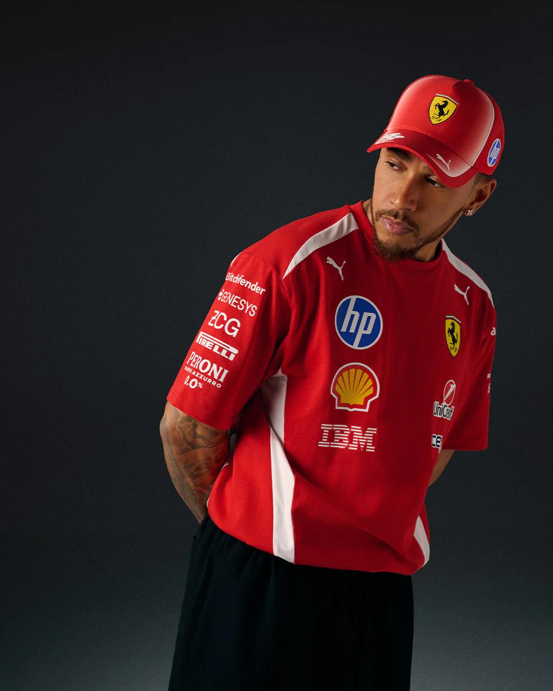 Lewis Hamilton in a red Ferrari team shirt and cap, looking to his right.