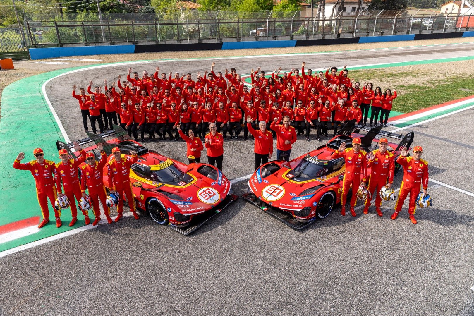 Ferrari AF Corse team members pose with two red 499P race cars on a track.