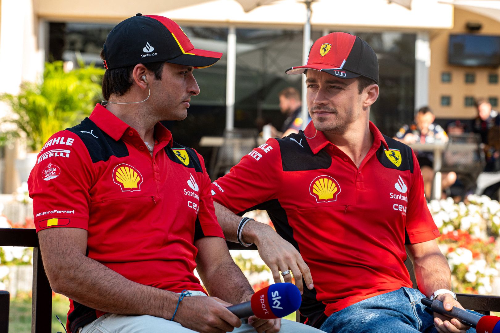 Carlos Sainz and Charles Leclerc in Ferrari team uniform giving an interview.