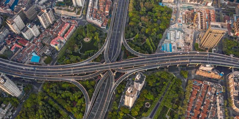 Aerial view of a sprawling multi-level highway interchange weaving through a dense Chinese city