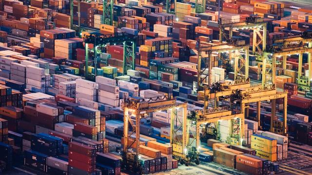 Aerial view of a densely packed container terminal with stacked shipping containers and gantry cranes