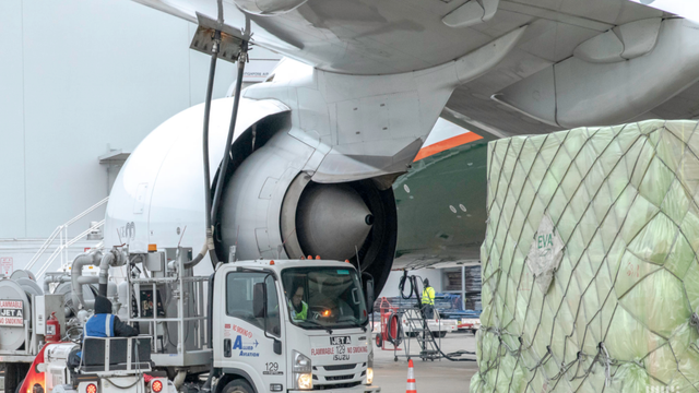 Cargo freighter aircraft with open nose door being loaded with palletized freight from a truck on the tarmac