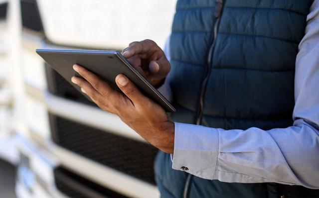 Close-up of a worker using a tablet beside a truck