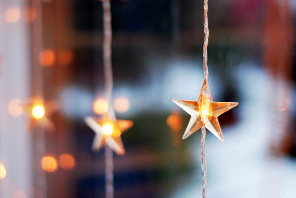 Close-up of glowing star-shaped string lights against blurred warm bokeh.