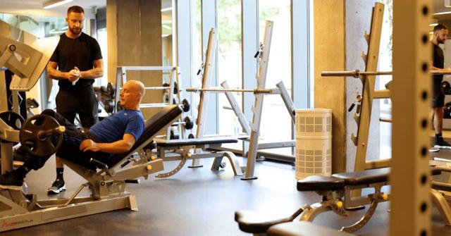 Gym interior with a man on a leg-press machine and a Rensair air purifier among the equipment