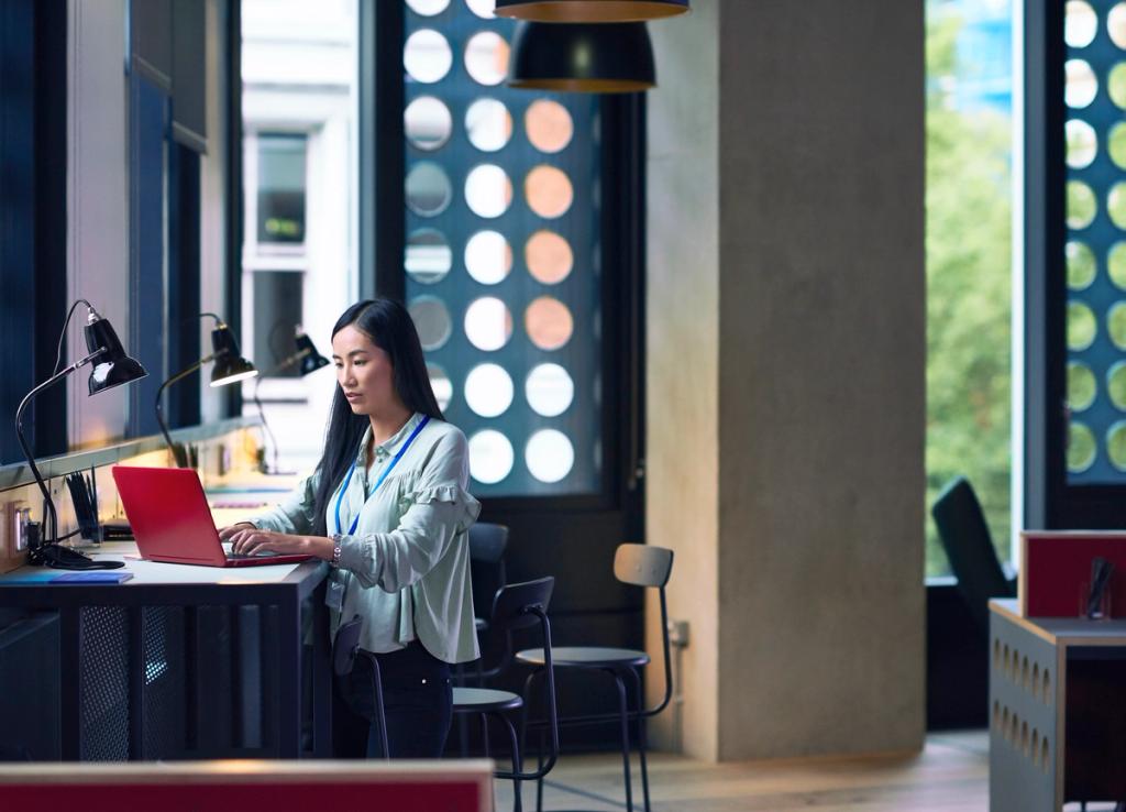 Woman working on a laptop at a desk in a modern office space.