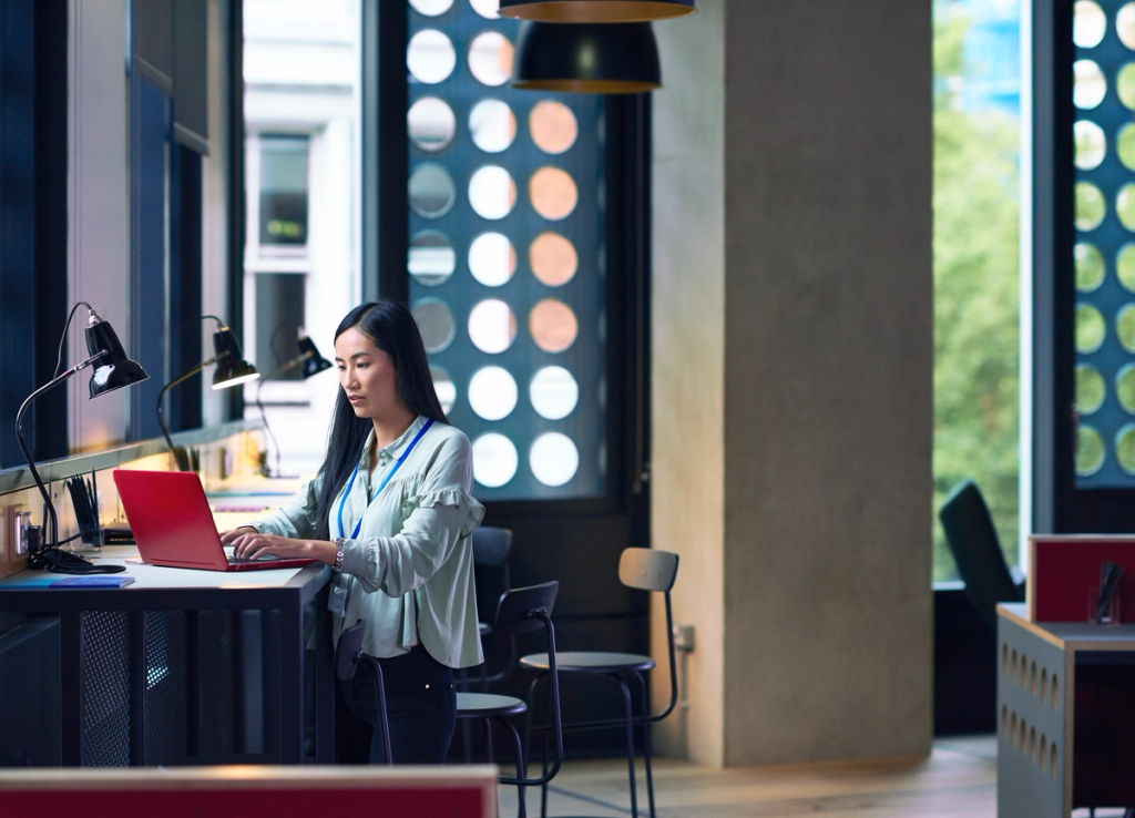 Woman working on a laptop at a desk in a modern office space.