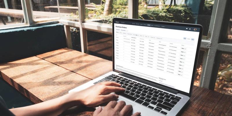 Hands type on a laptop showing the Flexport Purchase Orders dashboard with a table of POs and statuses.