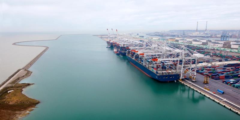 Aerial view of a container ship berthed at a port terminal with gantry cranes and stacked containers