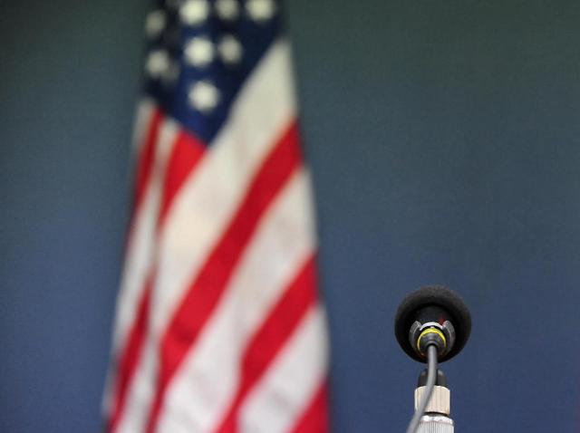 Microphone in sharp focus before a blurred American flag