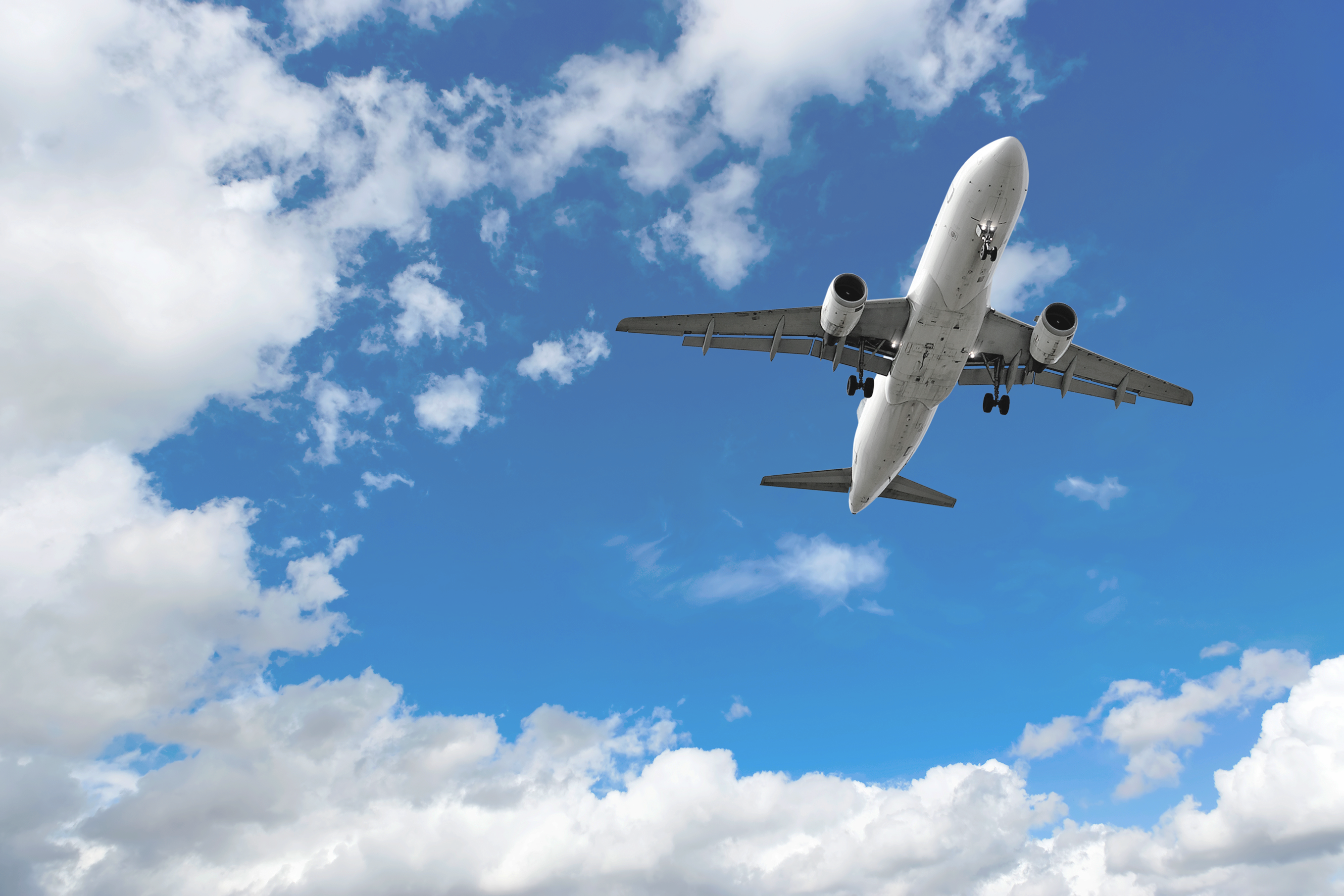 A commercial aircraft in flight approaches for landing against a cloudy sky.