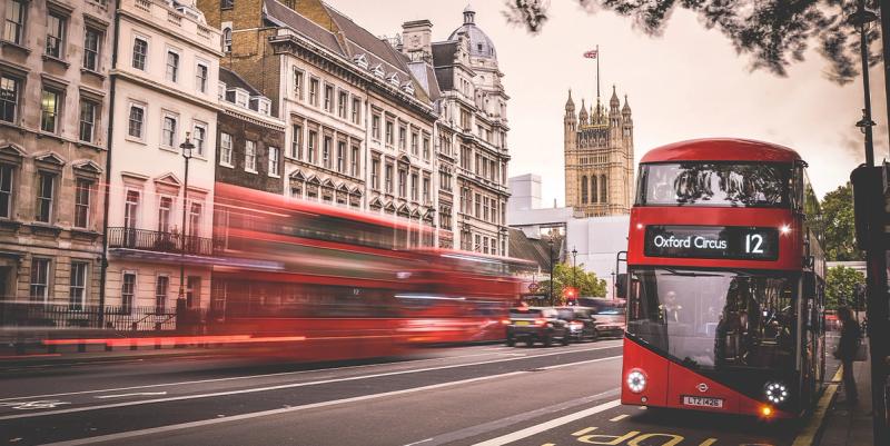 Red double-decker bus marked Oxford Circus 12 on a London street near the Houses of Parliament