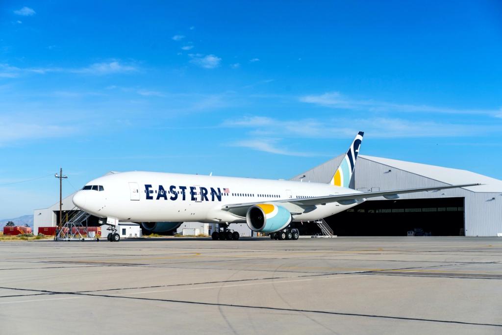 Eastern Air Boeing 777 parked on tarmac outside a hangar under clear blue sky
