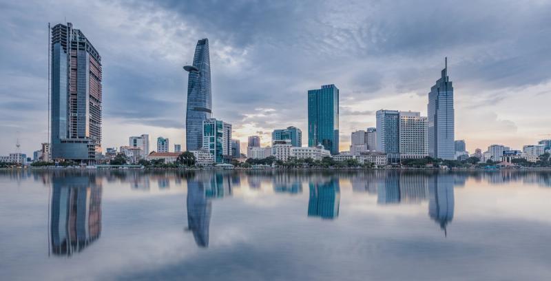 Ho Chi Minh City skyline with Bitexco tower reflected in calm water at dusk