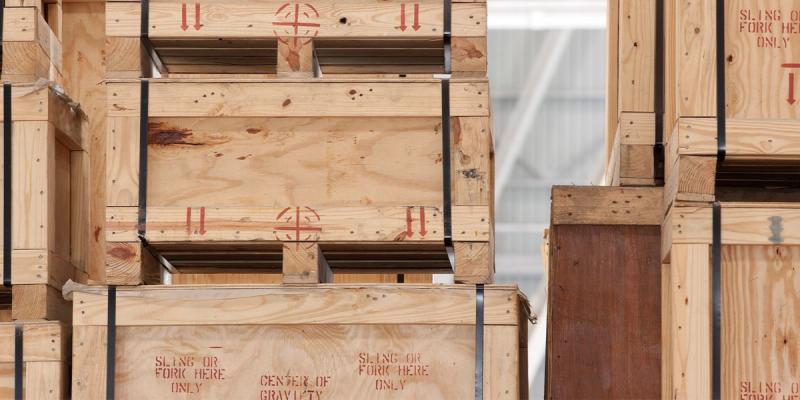 Stacked wooden shipping crates stenciled in red with Sling or Fork Here Only and Center of Gravity