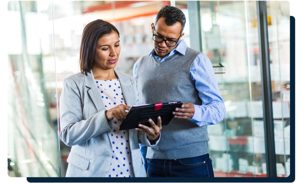Two professionals reviewing information on a tablet in a warehouse aisle