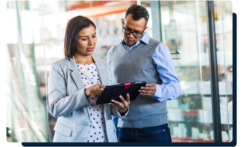 Two professionals reviewing information on a tablet in a warehouse aisle