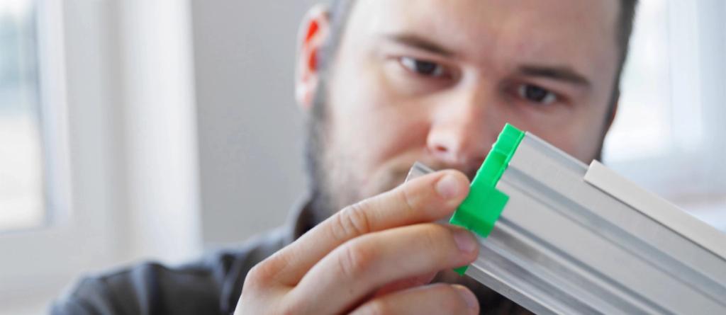 Bearded man inspecting an aluminum LED light fixture profile with a green connector