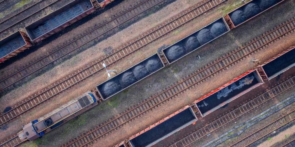 Aerial view of rail wagons loaded with dark coal and bulk cargo across diagonal train tracks