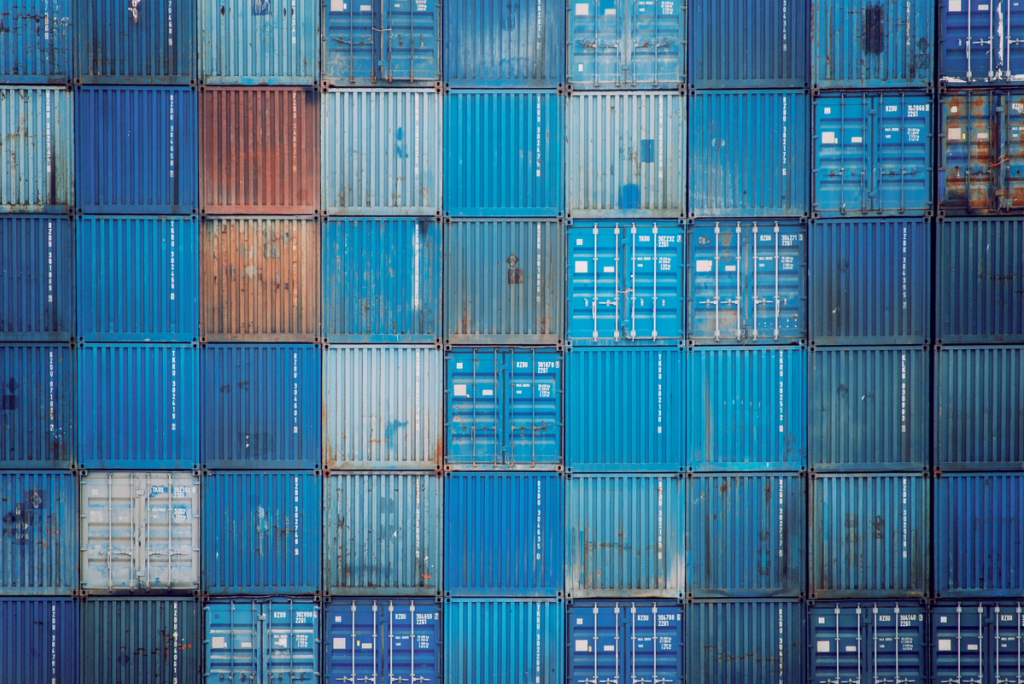 Stacked shipping containers arranged in rows at a cargo port or container terminal.