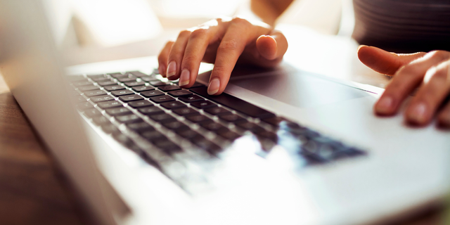 Close-up of hands typing on a laptop keyboard, representing a logistics manager working at a desk