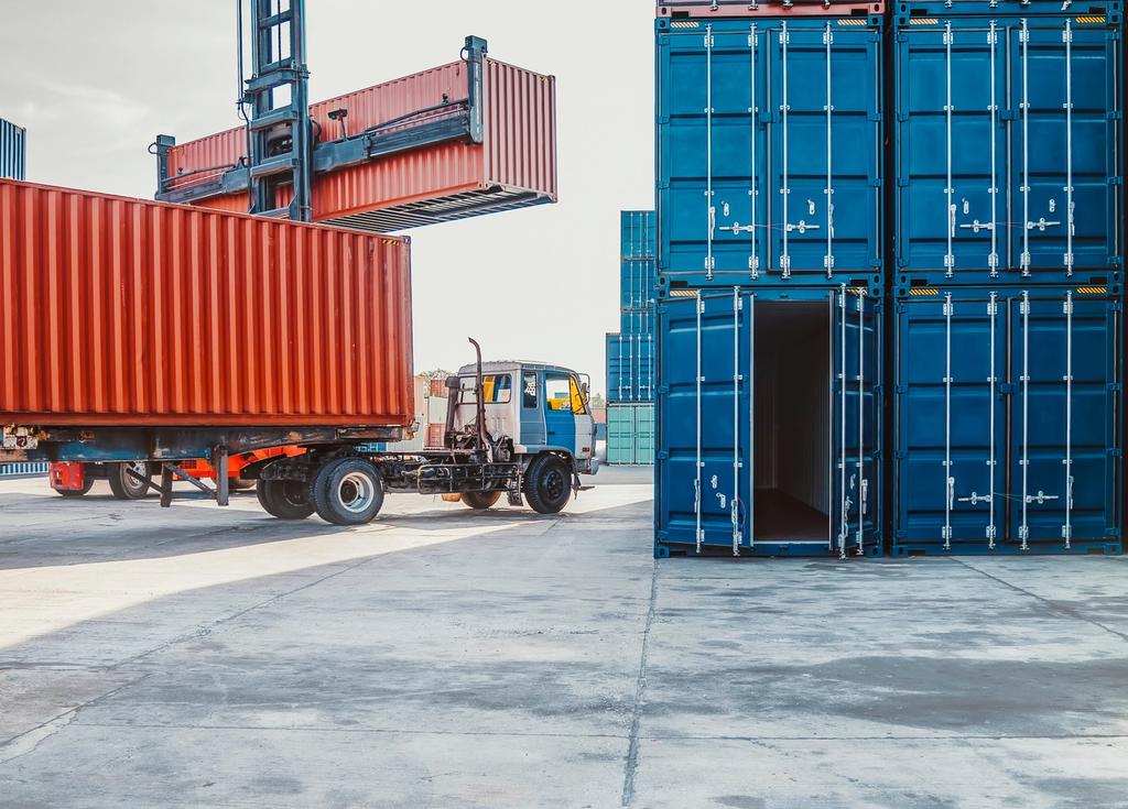 Container handling equipment loads shipping containers onto a truck at a port facility.