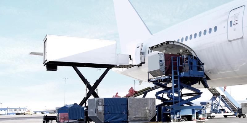 Cargo container on a scissor lift being loaded into the side hold of a parked widebody aircraft