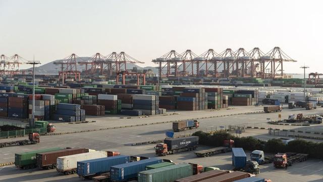 Container terminal with stacked shipping containers, gantry cranes, and trucks hauling containers at a busy port