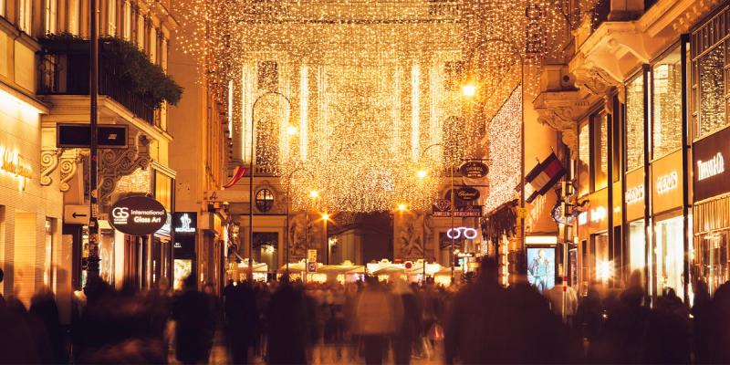 Crowded shopping street at night under glowing golden holiday string lights