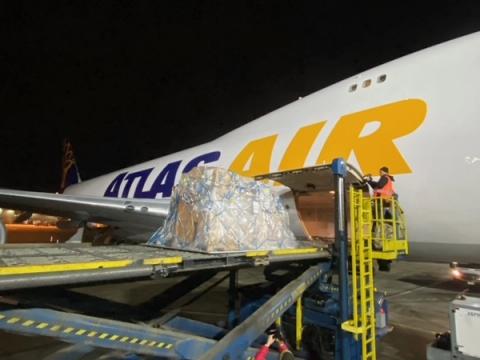 Ground crew loading a shrink-wrapped pallet into an Atlas Air cargo jet at night