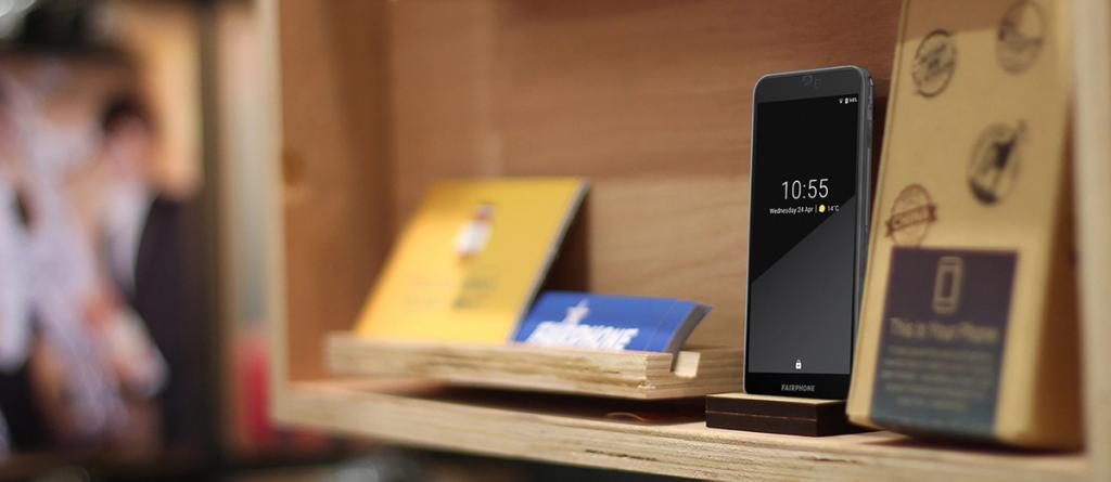 Fairphone smartphone displaying 10:55 on a wooden retail display shelf
