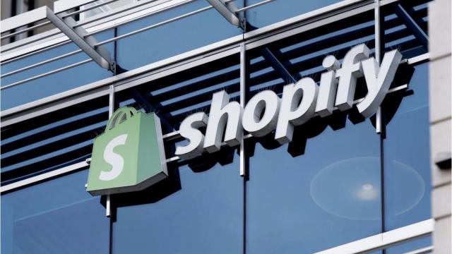 Shopify logo and wordmark mounted on a glass-and-steel office building exterior