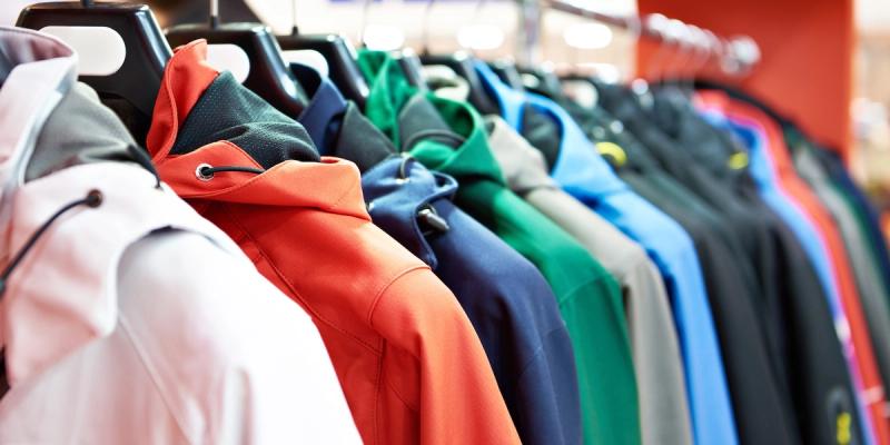 Rack of colorful outdoor jackets on hangers in a retail clothing store