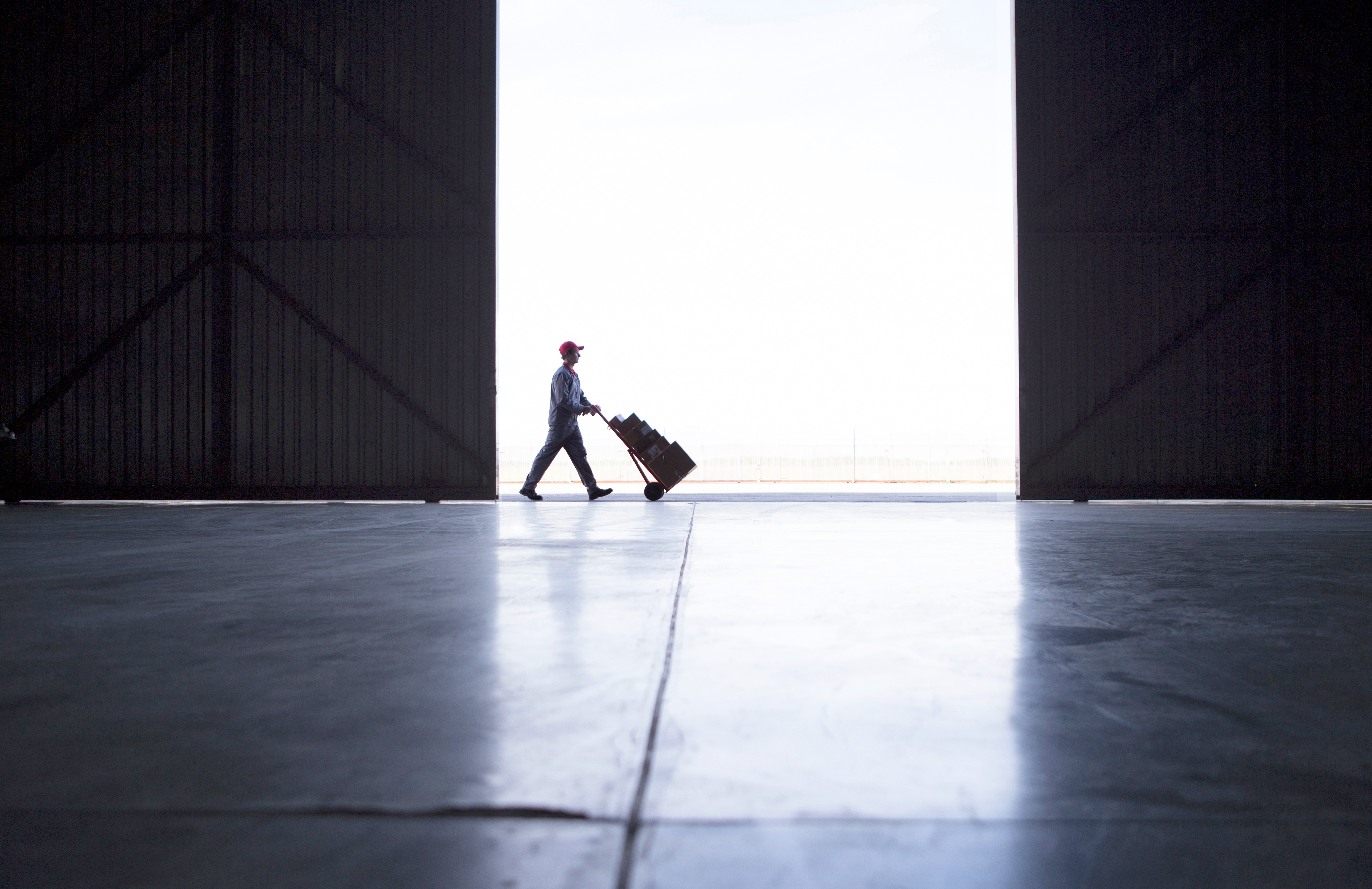 Female small business owner on the phone while working at a laptop, surrounded by shipping boxes in a warehouse office.