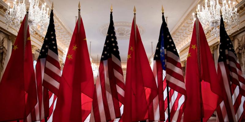 Rows of Chinese and U.S. flags arranged side by side in an ornate hall with chandeliers