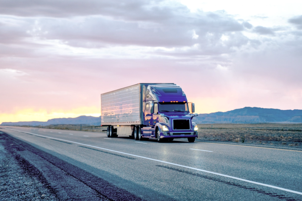 A semi truck with attached trailer drives on a highway.