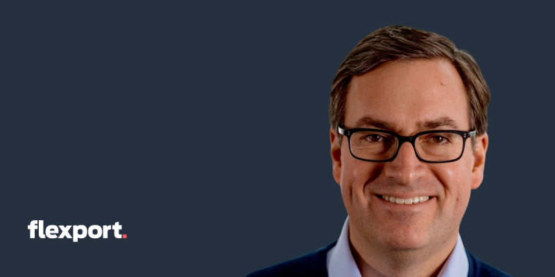 Headshot of a smiling man in glasses on a dark navy background with the Flexport logo